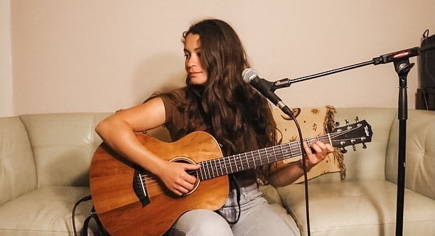 Emily Beck playing acoustic guitar.