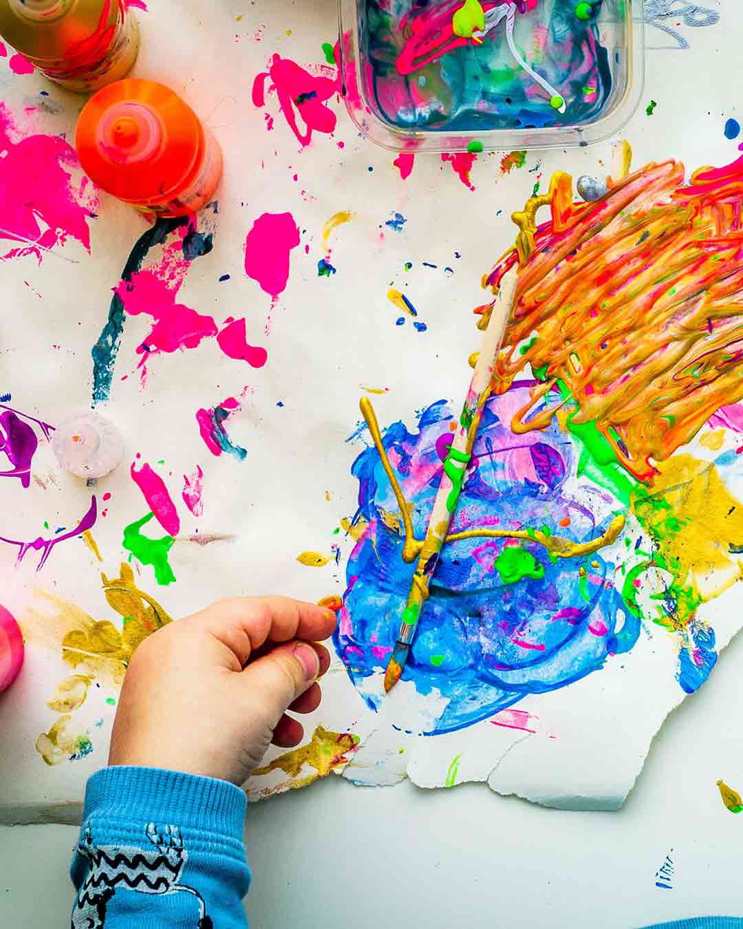 Stock image of child playing with colorful paints.