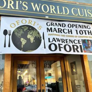 Exterior of Ofori's World Cuisine with a banner for the grand opening.