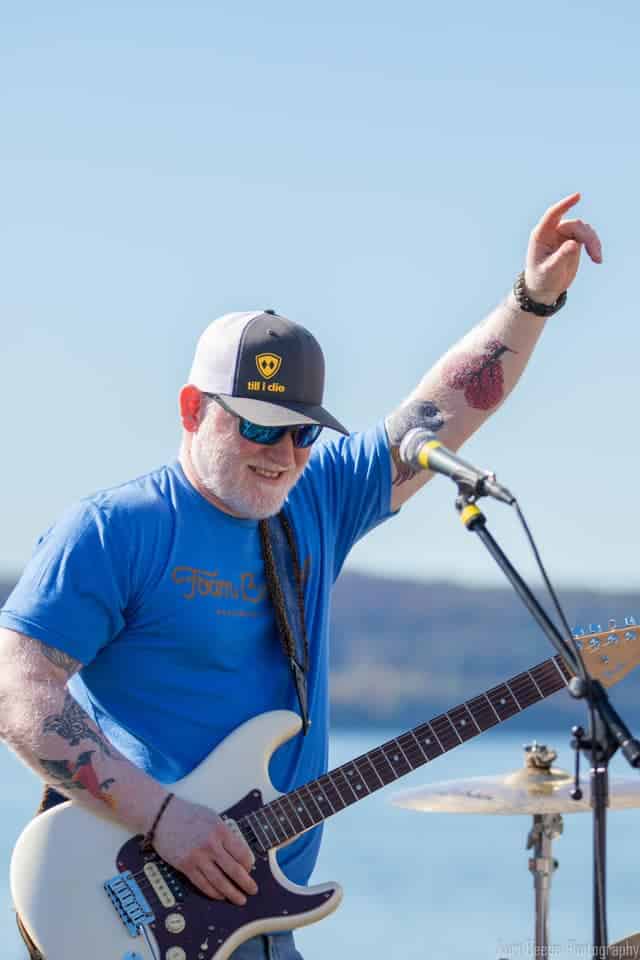 False Start guitarist raises his hand at the riverfront.