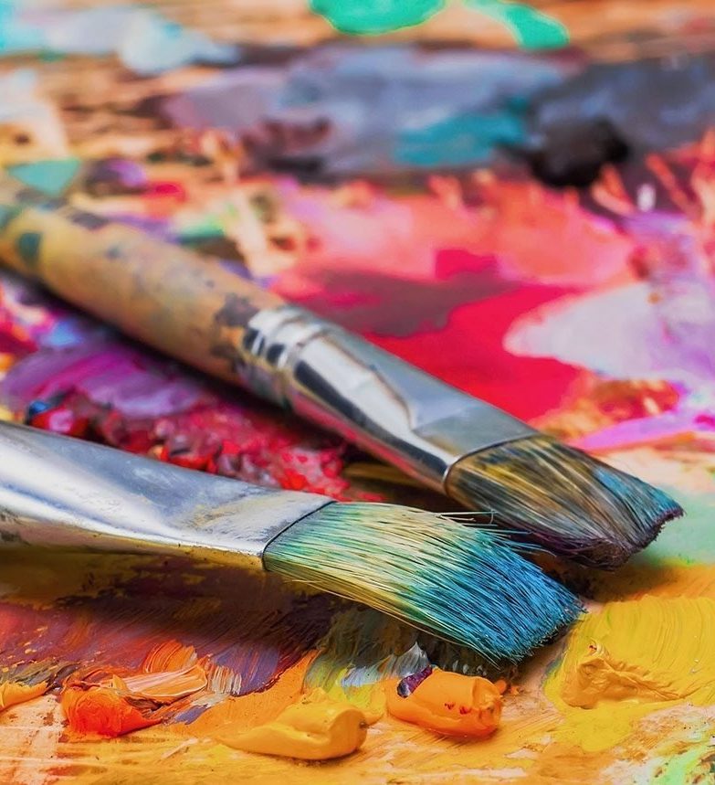 Used brushes on an artist's palette of colorful oil paint