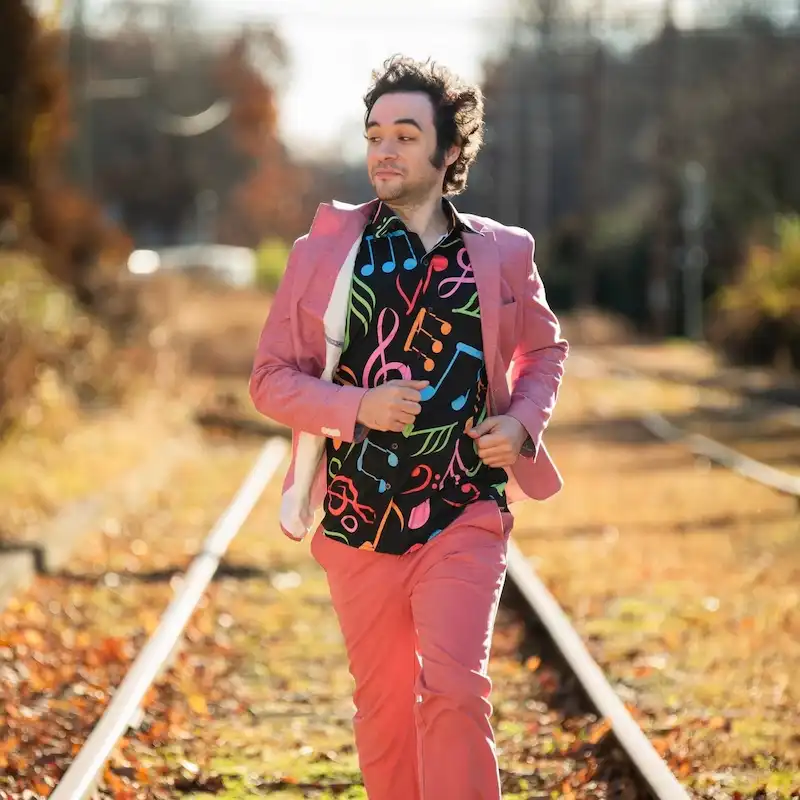 Albert Ahlf, frontman of the Ahlfabet Swing Group in a colorful shirt running on train tracks.
