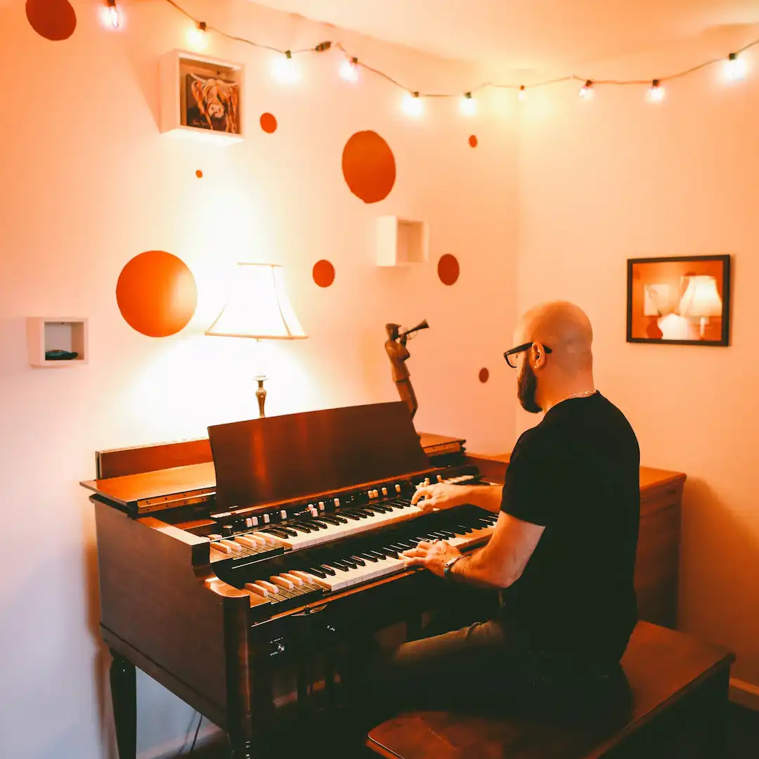 Jeremy Baum plays an organ in a minimalist room.